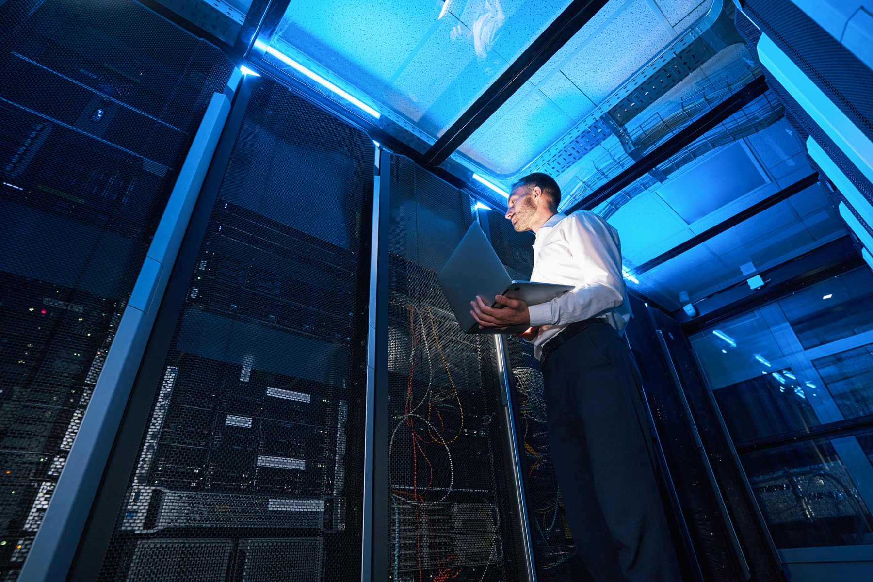 A technician with a laptop in a data centre aisle